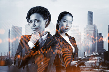 Two young attractive businesswoman in suits pondering about new venture capital and hi-tech start...