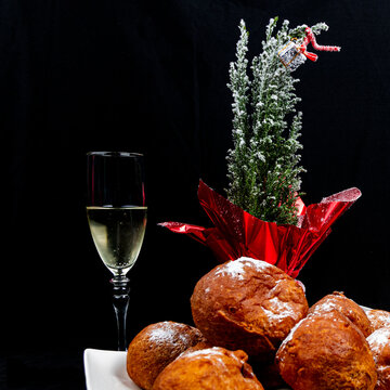 Deep fried buns (oliebol) and a glass of champagne is a typical Dutch tradition to celebrate new years eve in the Netherlands. The image is decorated with a small Christmas tree
