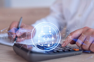 A businessman computing probability of risks in cyber security protection using calculator. Padlock Hologram icons over the working desk. Formal wear.