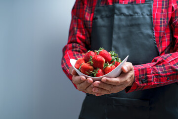 Man hands holding fresh strawberries in white bowl