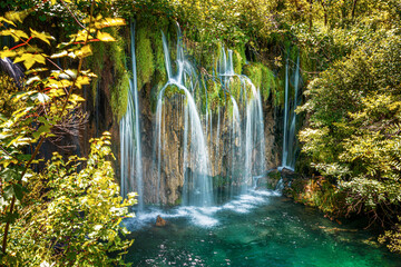 A beautiful picturesque waterfall in the rocky mountains among the forest.