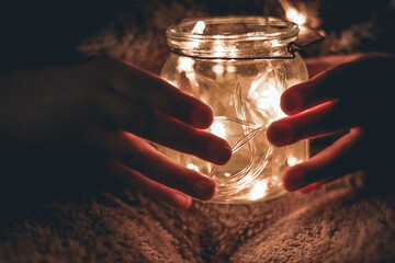 girl hands holding jar with lights. Selective focus