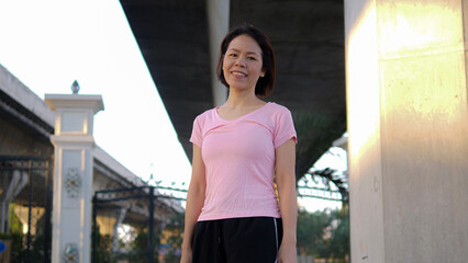 A good-looking Asian middle-aged woman with short black hair happily smiles at the camera. Healthy and beautiful woman getting ready to exercise in the morning Where the morning sun shines down