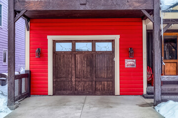 Rustic wooden door with glass panes of an attached garage of home with red wall