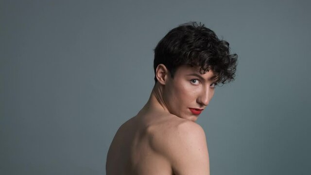Portrait of a transgender with makeup posing on grey background. Close-up. Masculine and feminine characteristics in one person. Gender identity concept 4k