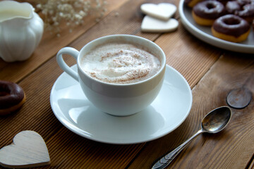 Cup of coffee,milk saucer and donuts, on wooden table with copy space.