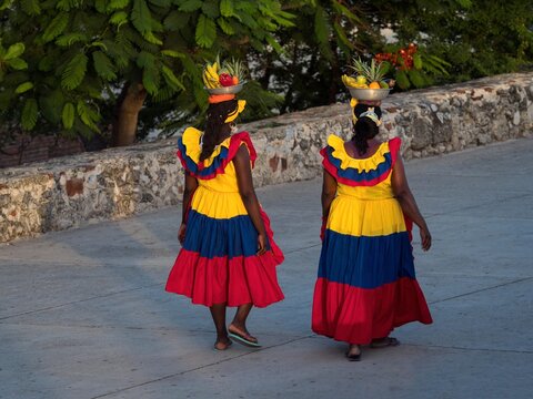 Afrocolombian women fruit vendor seller in colombian colored dress skirt costume walking in Cartagena de Indias Colombia