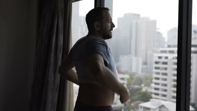 Man in panties wearing T-shirt and admire view form window at home