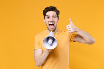 Young unshaved surprised happy student man 20s in casual basic t-shirt screaming in megaphone...