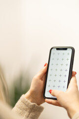 Girl holding smartphone in woman hands, browsing internet or application with blank screen mock-up for your design at home office with blurry background with free space for custom text