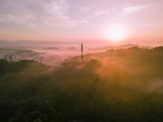 Aerial view of 5G Communication tower during morning sunrise with clouds, mists and fog