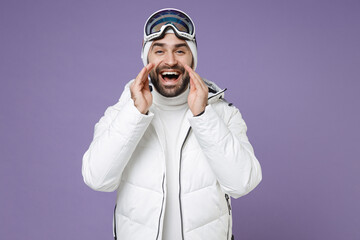 Funny skier man in white windbreaker jacket ski goggles mask scream news with hands near mouth spend extreme weekend winter in mountains isolated on purple background. People lifestyle hobby concept.
