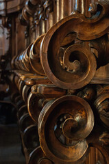 Detail einer alten, geschnitzten  Bank in einer Kirche  in Italien. Der Blick geht entlang einer Reihe von Sitzplätzen