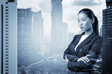 Prosperous Asian businesswoman in suit in crossed arms pose. Bangkok cityscape. The concept of...