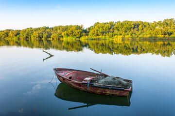 A wooden boat in the river, fishing boat in a calm lake water/old wooden fishing boat, wooden fishing boat in a still lake water