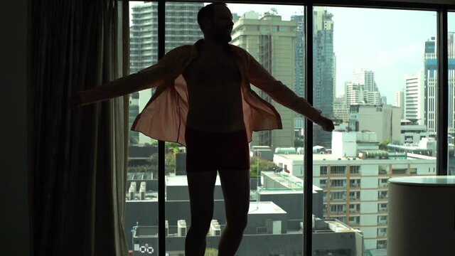 Excited man in underwear dancing by window at home, super slow motion