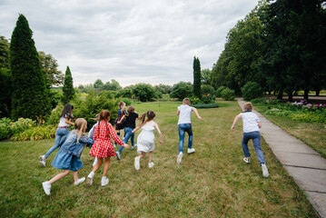 Fototapeta premium A group of school children runs in the Park in the summer. Happiness, lifestyle. Happy childhood
