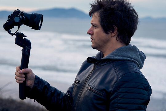 man recording a blog on the coast outside on a cloudy day. blogger concept