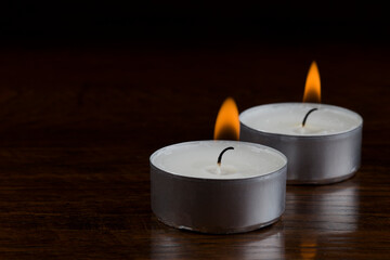 Fototapeta na wymiar burning tealight candle pair in the dark