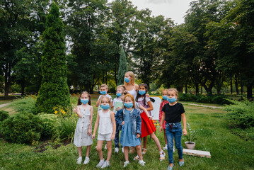 Obraz premium A class of masked school children is engaged in outdoor training during the epidemic. Back to school, learning during the pandemic
