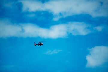 Black helicopter flying in the blue sky