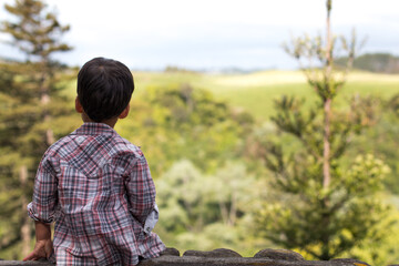 Thoughtful boy sitting in a park surrounded by trees in a calm and peaceful setting