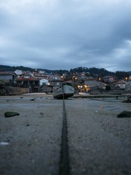 Stranded beached fishing boat vessle ship on coastline shore of seaside town village Combarro Galicia Spain at low tide