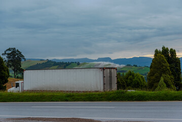 Fototapeta na wymiar truck with container of merchandise in highway with landscape of potato production area. Boyacá. Colombia.