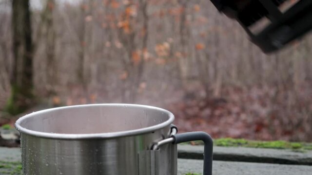 pouring boiling water into the tin cup in the woods
