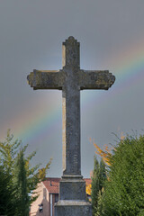 Gro&szlig;es Steinkreuz vor einem Regenbogen