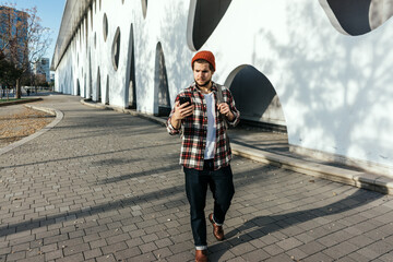 Portrait of modern young man with smartphone walking down the street © Rymden