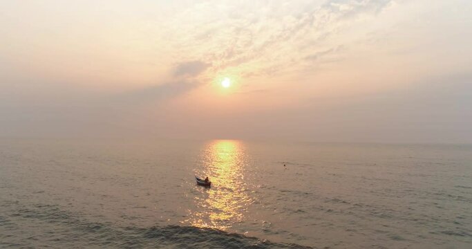 A fisherman in a boat with the sun setting in the back capture with a drone in the Arabian sea from the coast of Mumbai, where the next coastal road project will be coming up.