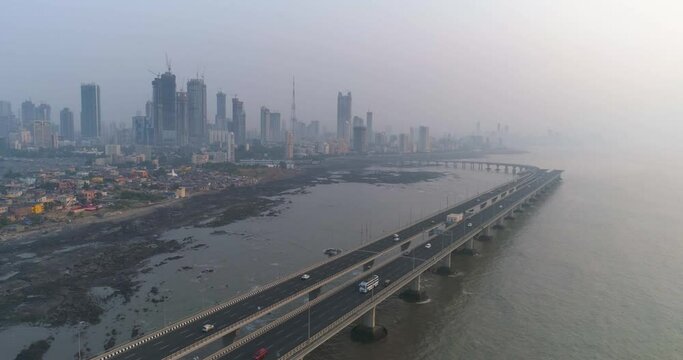 A drone shot at Bandra Worli Sea Link seen from an aerial view in slow motion. Cinematic drone movement with the iconic Mumbai Sea Link at the forefront and the city view in the background.