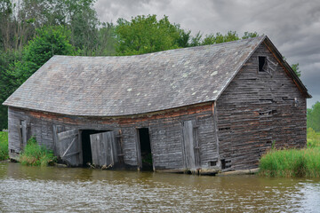 Fototapeta na wymiar Old abandoned barn on the edge of the Champlain canal
