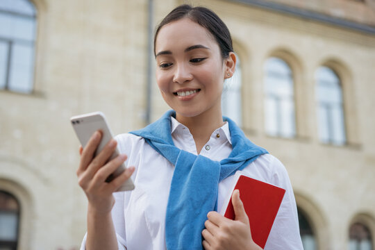 Beautiful asian woman using mobile phone, communication, looking at digital screen, walking on the street