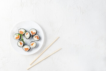Sushi rolls in the form of a heart with chopsticks on a white plate. Valentine's Day. Horizontal orientation, copy space.