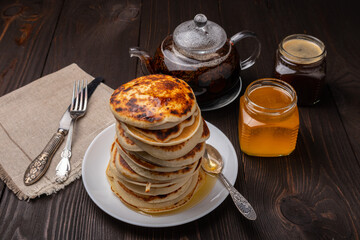 stack of pancakes with honey on a dark wooden background