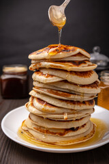 stack of pancakes with honey on a dark wooden background