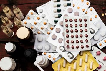 Colorful pills and capsules on wooden table