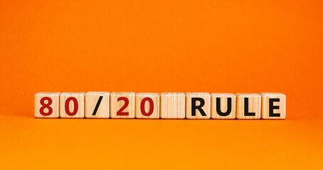 80 on 20 rule symbol. Wooden cubes with words '80 on 20 rule'. Beautiful orange background, copy space. Business and 80 on 20 rule concept.