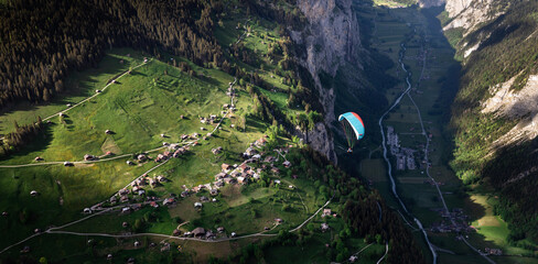 Parasailor glides over lush valley and lofty clouds