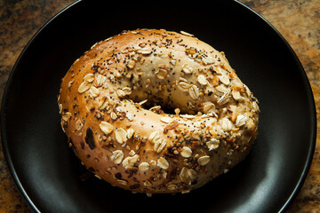 Whole everrything bagel on a dark plate close up