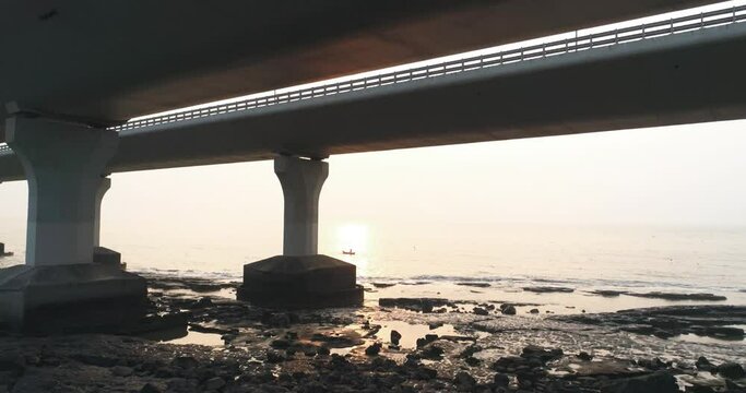 Fly by under the Bandra Worli Sea Link, revealing a fisherman in a boat with the sun setting in the back. Mumbai's iconic landmark looks even more cinematic in aerial view when captured with a drone.