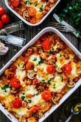 Noodle casserole with minced meat, mozzarella cheese and vegetables on wooden table
