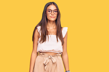 Young hispanic woman wearing casual clothes and glasses relaxed with serious expression on face....