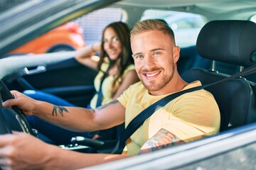 Young couple smiling happy driving car,