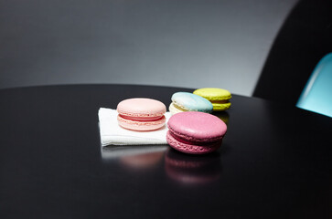 Colorful macaroons on paper napkin on dark table with copy space
