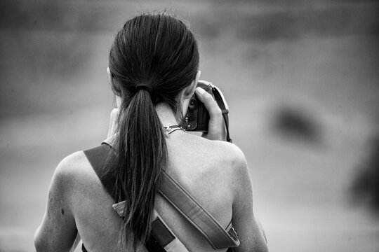 Back view of a caucasian female tourist photographing a National Park landscape