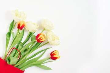 Red and yellow tulips in a red gift bag on a white background with copying space. Valentine's Day or Mother's Day Greeting Card