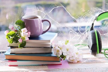 A cup of coffee, a stack of books, apple flowers on a wooden windowsill, spring, the concept of home comfort, reading, learning